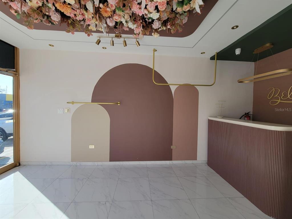 A retail space features arched wall murals, gold clothing racks, and a floral ceiling installation — BB 29 AVE SANTA JUANITA, BAYAMON, PR