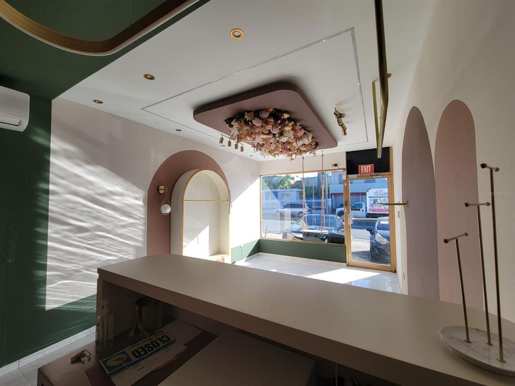 A retail space features a floral ceiling installation, arched wall cutouts, and a front counter — BB 29 AVE SANTA JUANITA, BAYAMON, PR