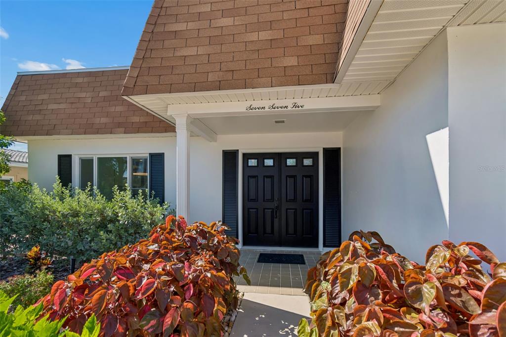 A front entrance features a double door, a shingled roof, and landscaping in the foreground — 775 CAPRI BOULEVARD, TREASURE ISLAND, FL