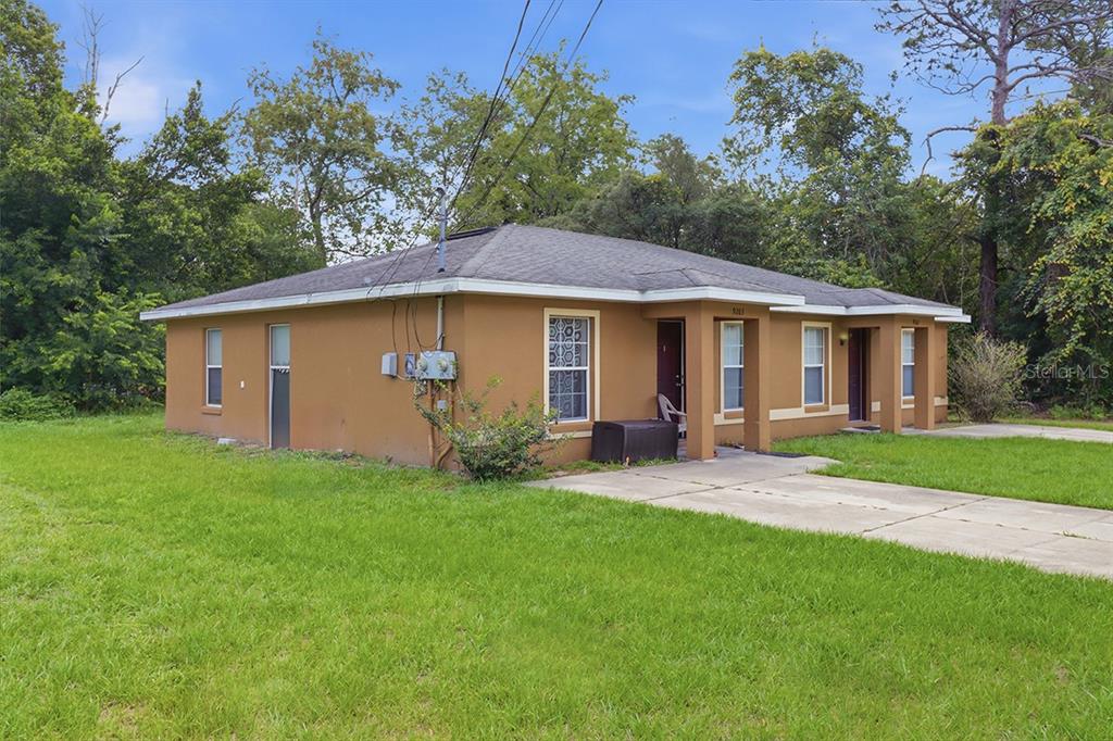 A tan, single-story duplex with a hip roof and concrete driveway sits on a lawn — 9261 N PEACHTREE WAY, CITRUS SPRINGS, FL