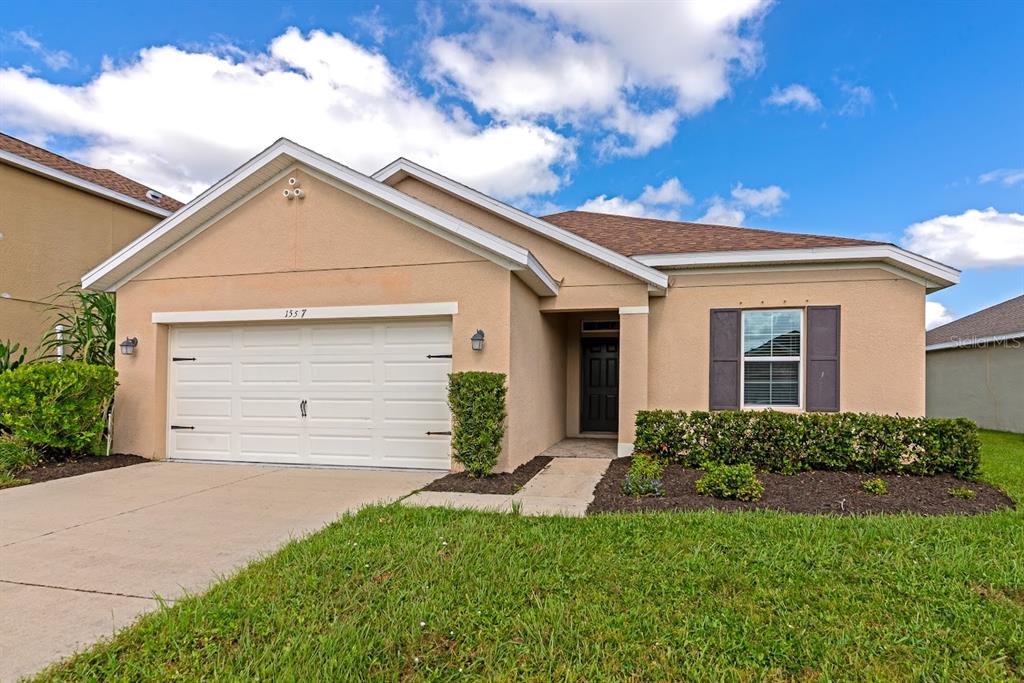A single-story house with a beige stucco exterior, a two-car garage, and a front lawn — 15517 ROSE GROVE DRIVE, BRADENTON, FL
