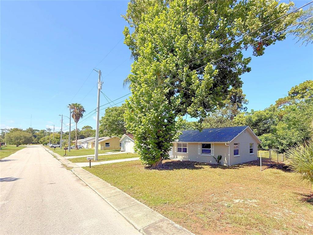 A single-story house with a large tree in the front yard along a residential street — 15839 VILLA DRIVE, HUDSON, FL