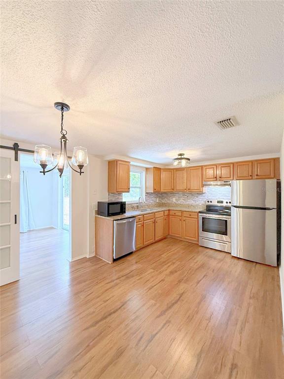 A kitchen with wood cabinets, stainless steel appliances, and wood-look flooring — 15839 VILLA DRIVE, HUDSON, FL