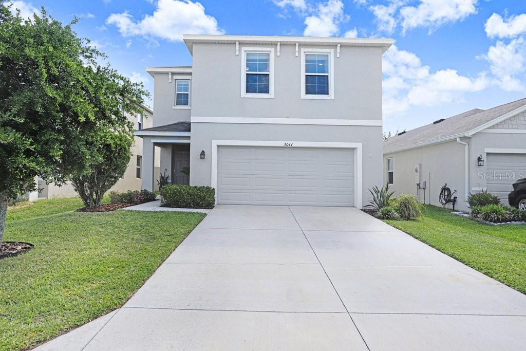 A two-story house with a light gray exterior, a two-car garage, and a concrete driveway — 3044 SUNCOAST PLAINS DRIVE, ODESSA, FL