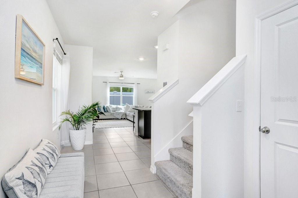 A bright entryway features light tile flooring, a staircase with carpet, and a view beyond — 3044 SUNCOAST PLAINS DRIVE, ODESSA, FL
