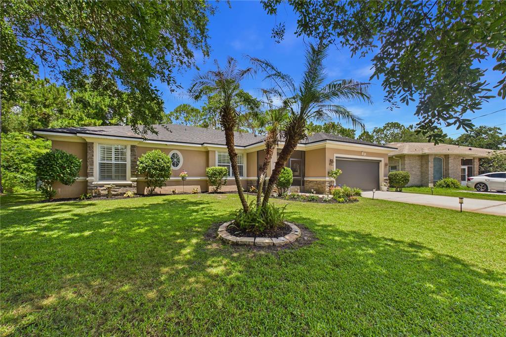 A single-story house with a tan exterior, stone accents, and a palm tree in front — 49 FANSHAWE LANE, PALM COAST, FL