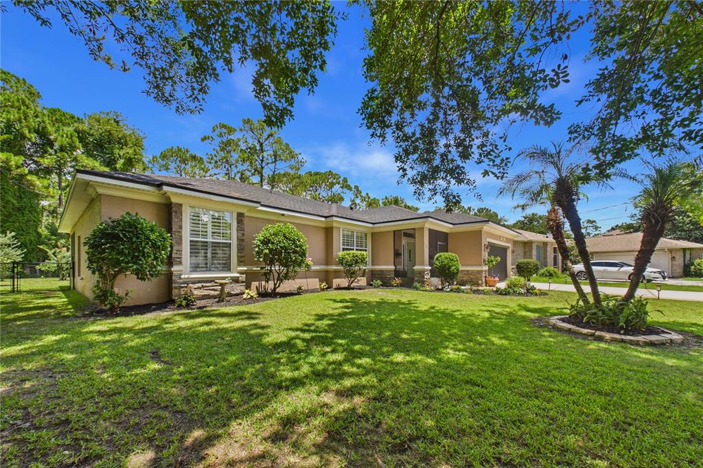 A single-story house with a tan stucco exterior, stone accents, and a landscaped front yard — 49 FANSHAWE LANE, PALM COAST, FL