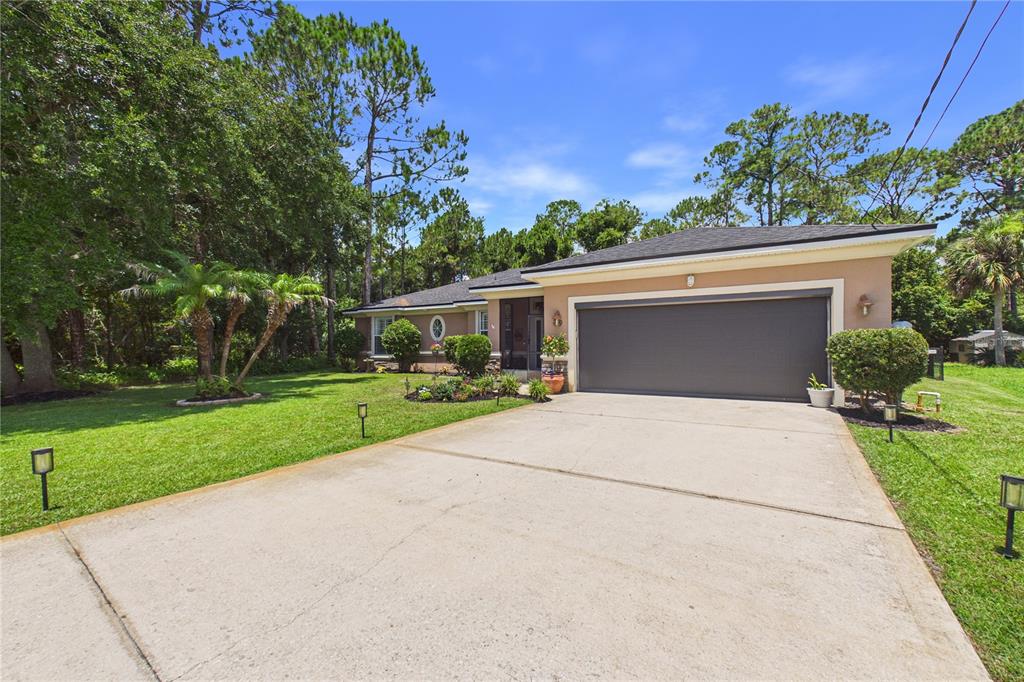 A single-story house with a two-car garage and a concrete driveway sits on a lawn — 49 FANSHAWE LANE, PALM COAST, FL
