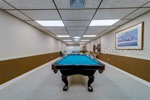 A pool table sits in the center of a room with beige walls and carpet — 17920 GULF BOULEVARD UNIT 1203, ST PETERSBURG, FL