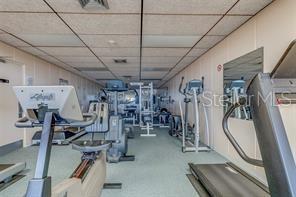 A gym room features various exercise machines, a drop ceiling, and light-colored walls — 17920 GULF BOULEVARD UNIT 1203, ST PETERSBURG, FL