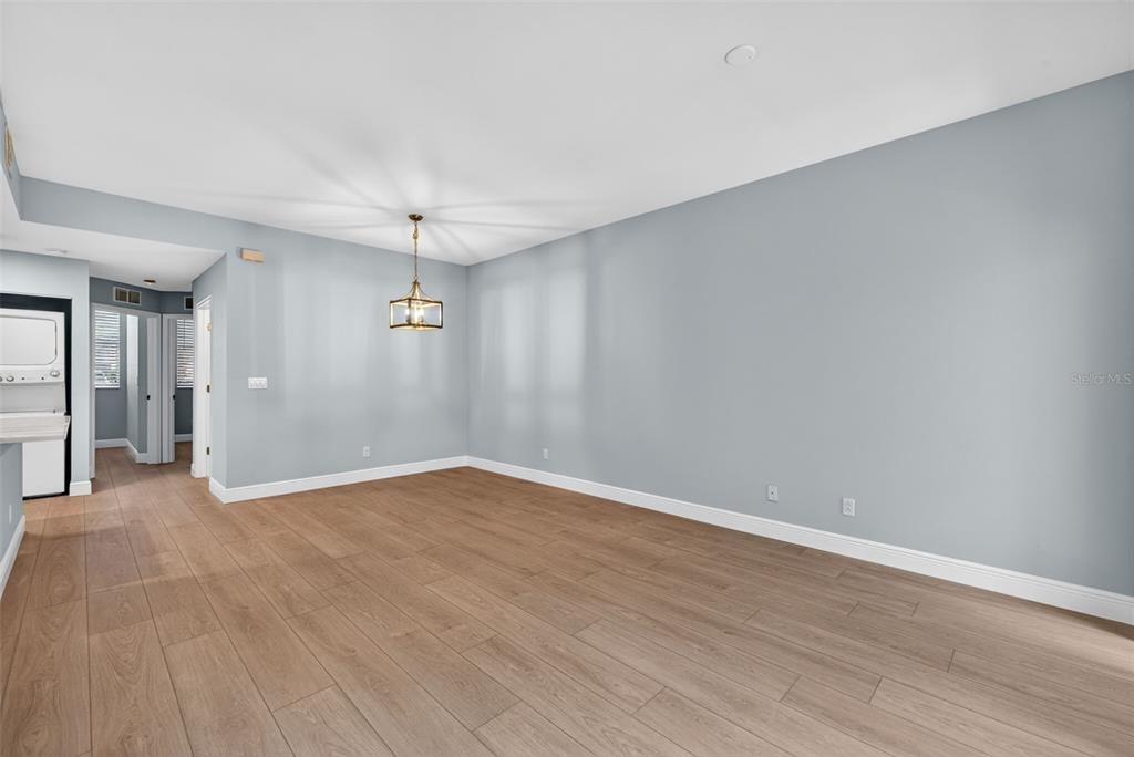 An empty dining room features light gray walls, wood-look flooring, and a modern pendant light — 4109 BELLASOL CIRCLE UNIT 1113, FORT MYERS, FL