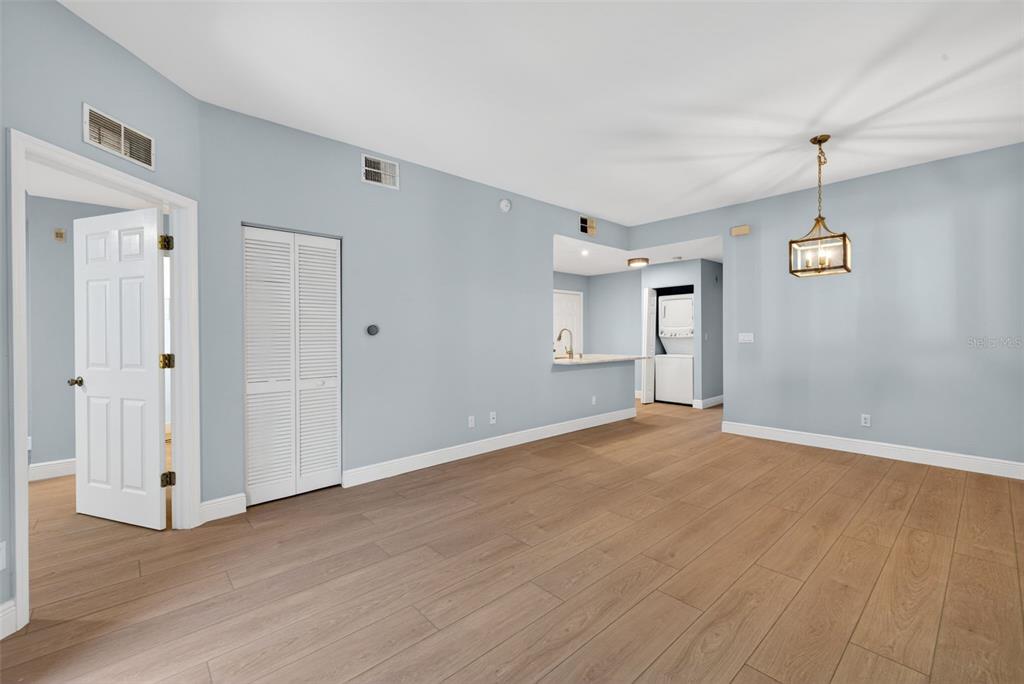 An empty room with light blue walls, wood-look flooring, a white closet, and a pendant light — 4109 BELLASOL CIRCLE UNIT 1113, FORT MYERS, FL