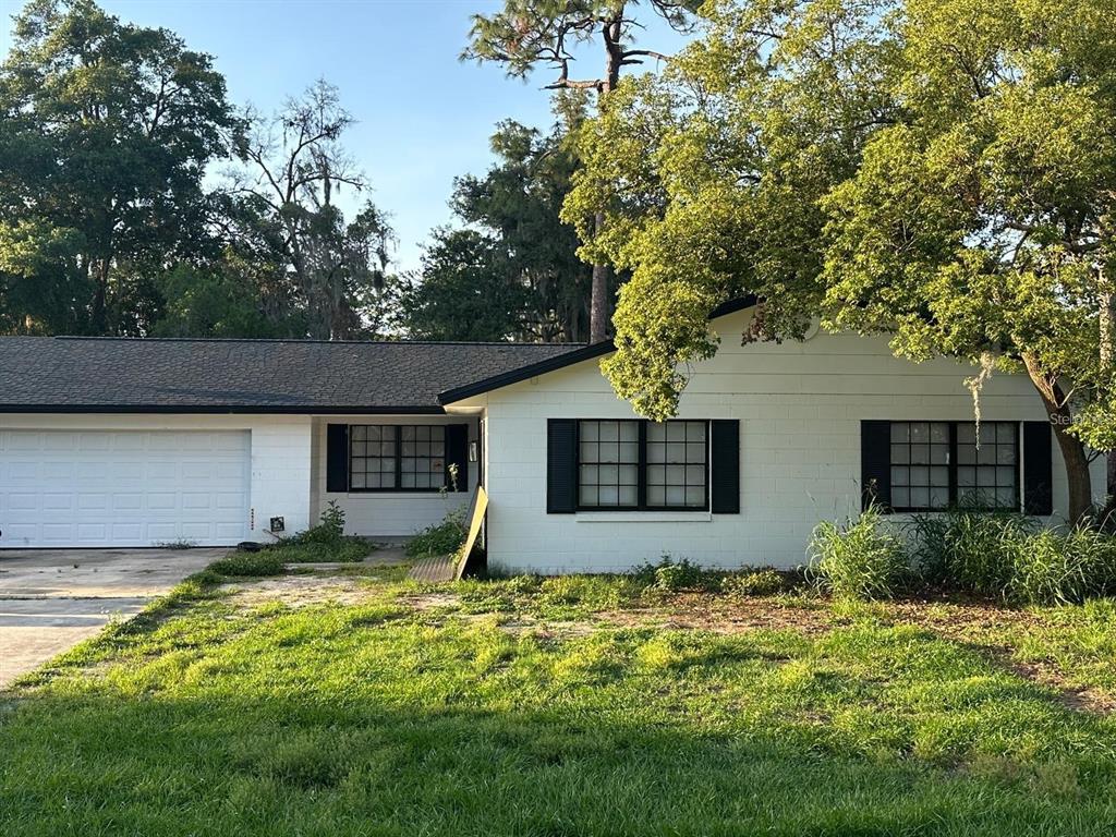 A single-story white house with a black roof, garage, and black-shuttered windows — 2643 BALKAN STREET S, APOPKA, FL