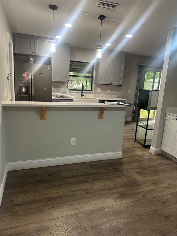 A kitchen with gray cabinets, white countertops, a breakfast bar, and wood-look flooring — 2643 BALKAN STREET S, APOPKA, FL