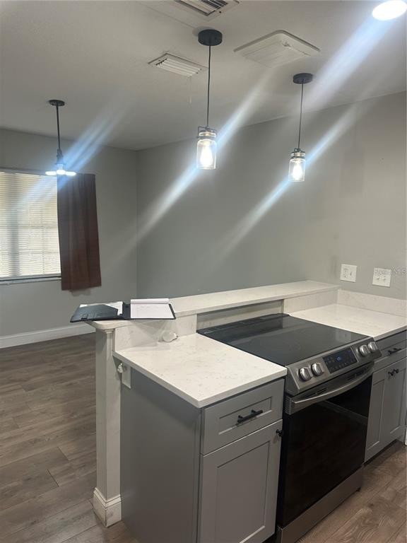A kitchen features gray cabinets, white quartz countertops, stainless steel appliances, and three pendant lights — 2643 BALKAN STREET S, APOPKA, FL