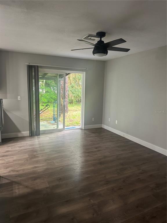 A living room with wood-look flooring, a ceiling fan, and a sliding glass door to outside — 2643 BALKAN STREET S, APOPKA, FL