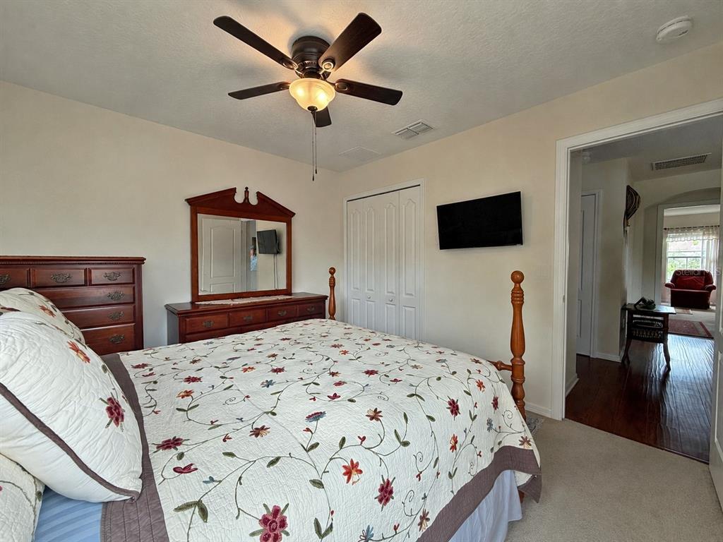 A bedroom features a bed with a floral quilt, a wooden dresser with a mirror, and a television — 2016 SCHULLER WAY, CASSELBERRY, FL