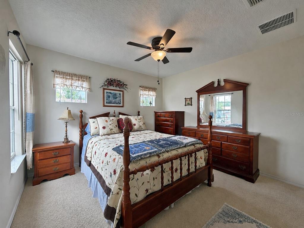 A bedroom features a wooden four-poster bed, matching dresser, nightstand, and beige wall-to-wall carpeting — 2016 SCHULLER WAY, CASSELBERRY, FL