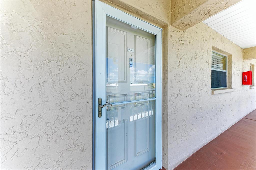 A white storm door with a glass panel leads into a unit numbered 434 — 3983 MACEACHEN BOULEVARD UNIT 434, SARASOTA, FL