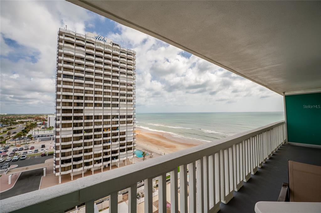 A balcony overlooks the ocean and a tall residential building with a parking lot below — 2800 N ATLANTIC AVENUE UNIT 1009, DAYTONA BEACH, FL