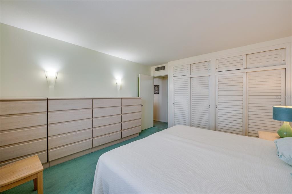 A bedroom features a large dresser, white louvered closet doors, and green carpeting — 2800 N ATLANTIC AVENUE UNIT 1009, DAYTONA BEACH, FL