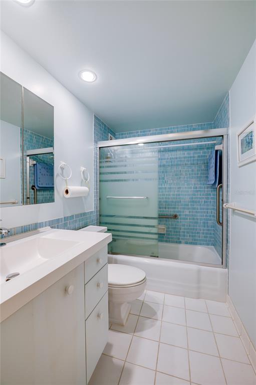 A bathroom features a white vanity, a toilet, and a tub with blue mosaic tiles — 2800 N ATLANTIC AVENUE UNIT 1009, DAYTONA BEACH, FL