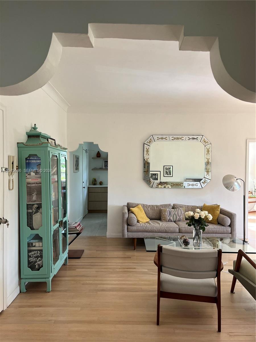 A living and dining room with light wood floors, a glass coffee table, and two armchairs — MIAMI BEACH, FL