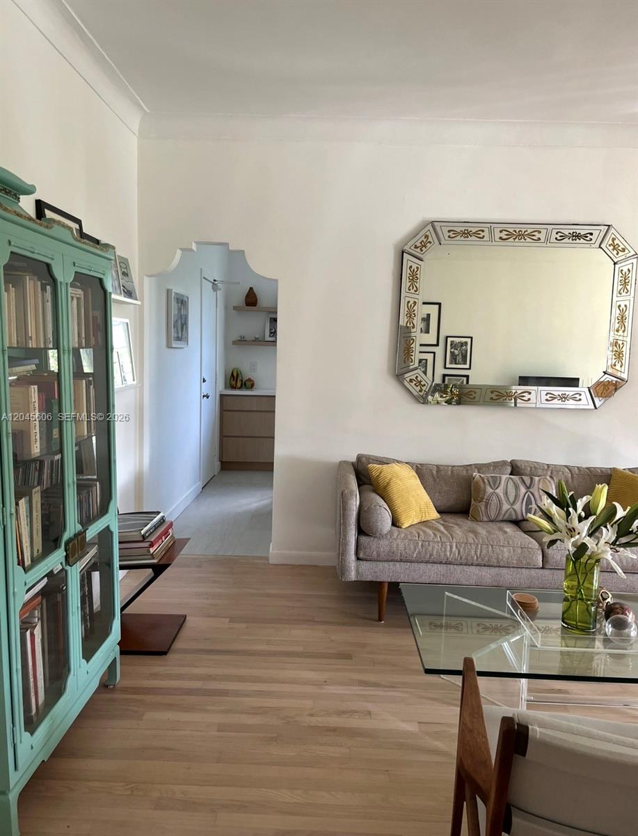 A living room features a teal cabinet, a grey sofa, and a large decorative mirror — MIAMI BEACH, FL