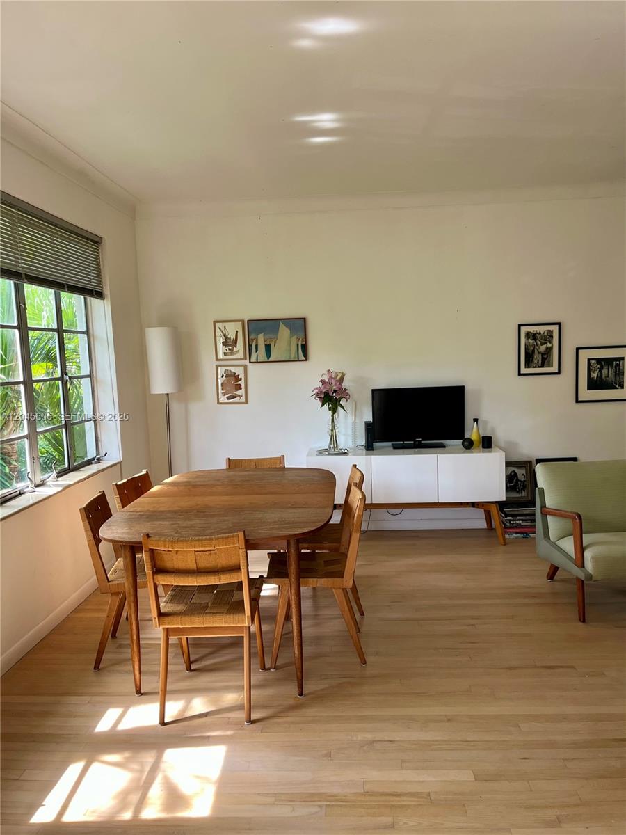 A dining area with a wooden table, woven chairs, and a white media console — MIAMI BEACH, FL