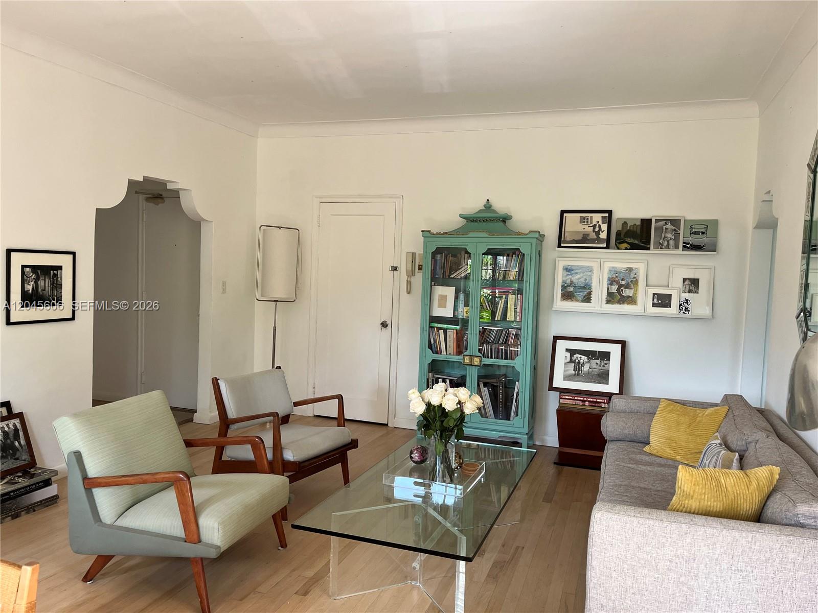 A living room features a teal cabinet, two armchairs, a glass coffee table, and a sofa — MIAMI BEACH, FL
