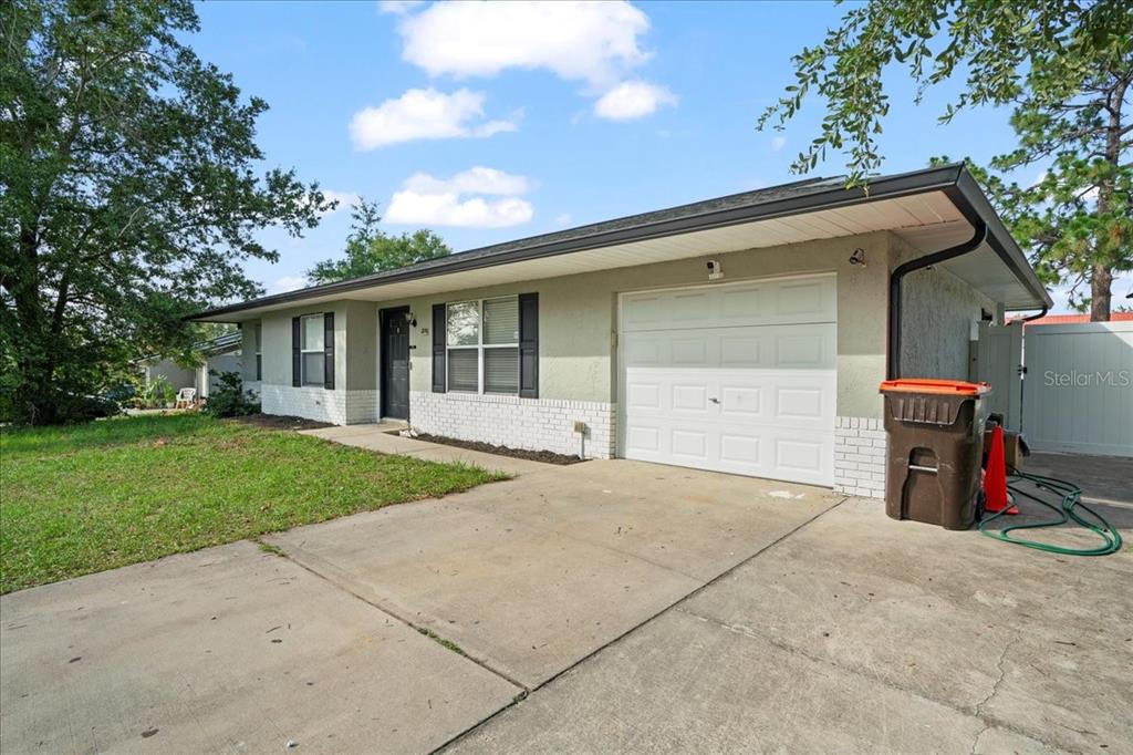 A single-story house with a white garage door, light-colored stucco walls, and a concrete driveway — 24 SAPPHIRE WAY, OCALA, FL