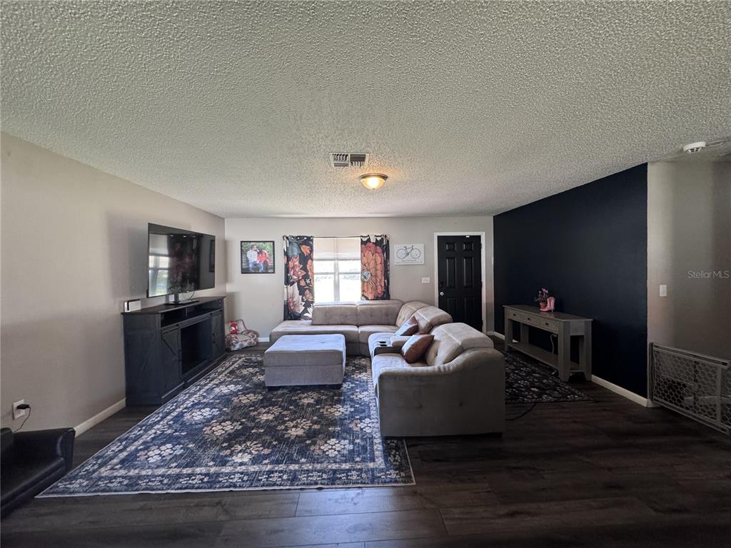 A living room features a sectional sofa, a large area rug, and a dark accent wall — 24 SAPPHIRE WAY, OCALA, FL
