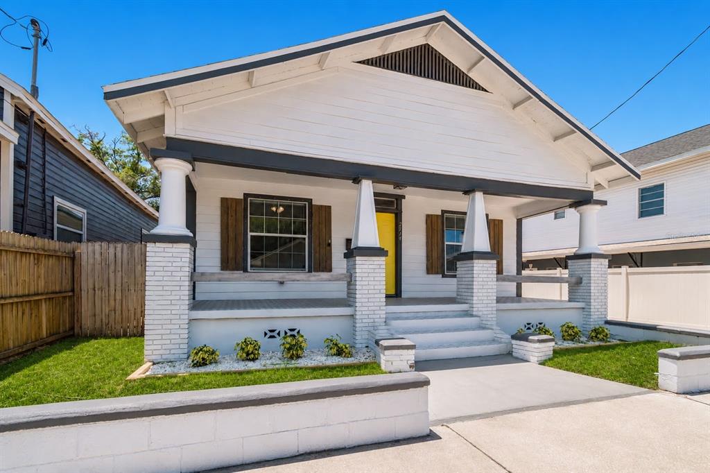 A white bungalow with a front porch, brick pillars, and a yellow front door — 2914 N 16TH STREET, TAMPA, FL