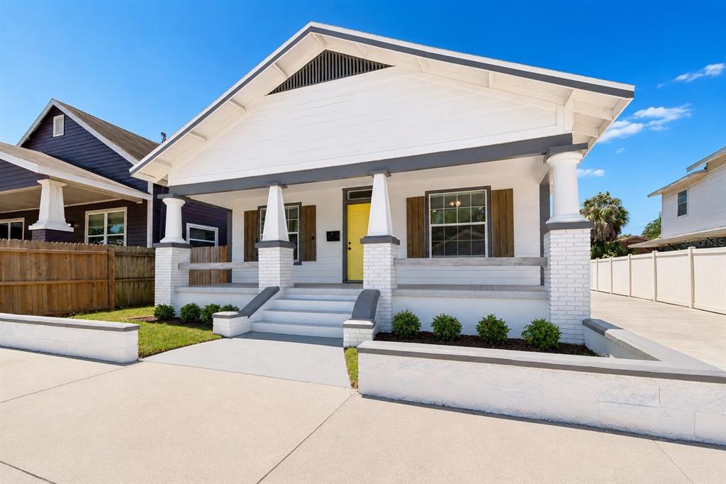 A white bungalow with a front porch, yellow door, and a concrete driveway — 2914 N 16TH STREET, TAMPA, FL