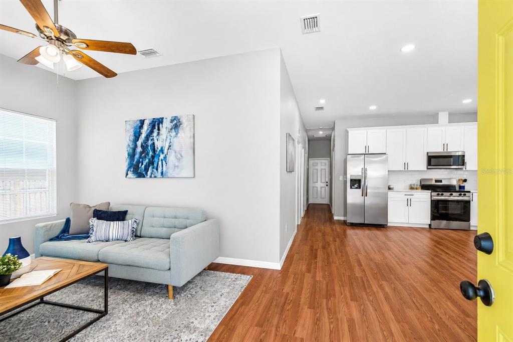 A living room with a light blue sofa opens into a kitchen with white cabinets — 2914 N 16TH STREET, TAMPA, FL