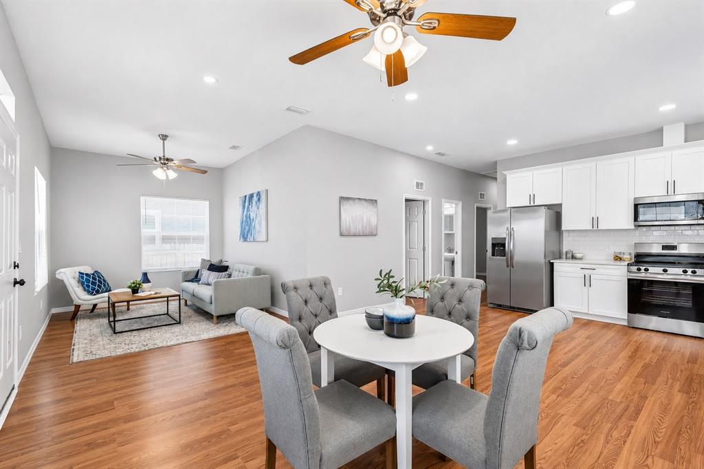 An open-concept living and dining area features wood-look flooring, white cabinets, and stainless appliances — 2914 N 16TH STREET, TAMPA, FL