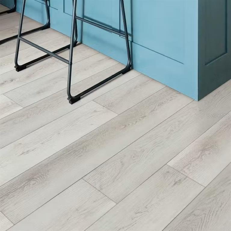 Light-colored wood-look flooring extends beneath a blue kitchen island and metal bar stools — 534 WINDY WILLOW WAY, ST CLOUD, FL