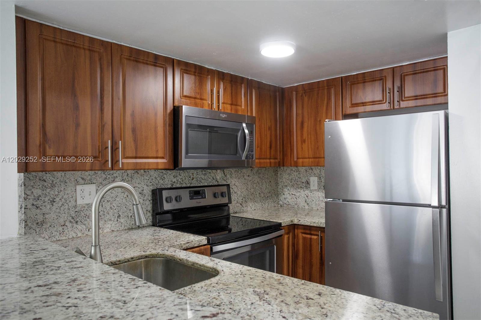 A kitchen features wood cabinets, granite countertops, and stainless steel appliances — 8580 NW 6th Ln # 205, Miami FL 33126, MIAMI, FL