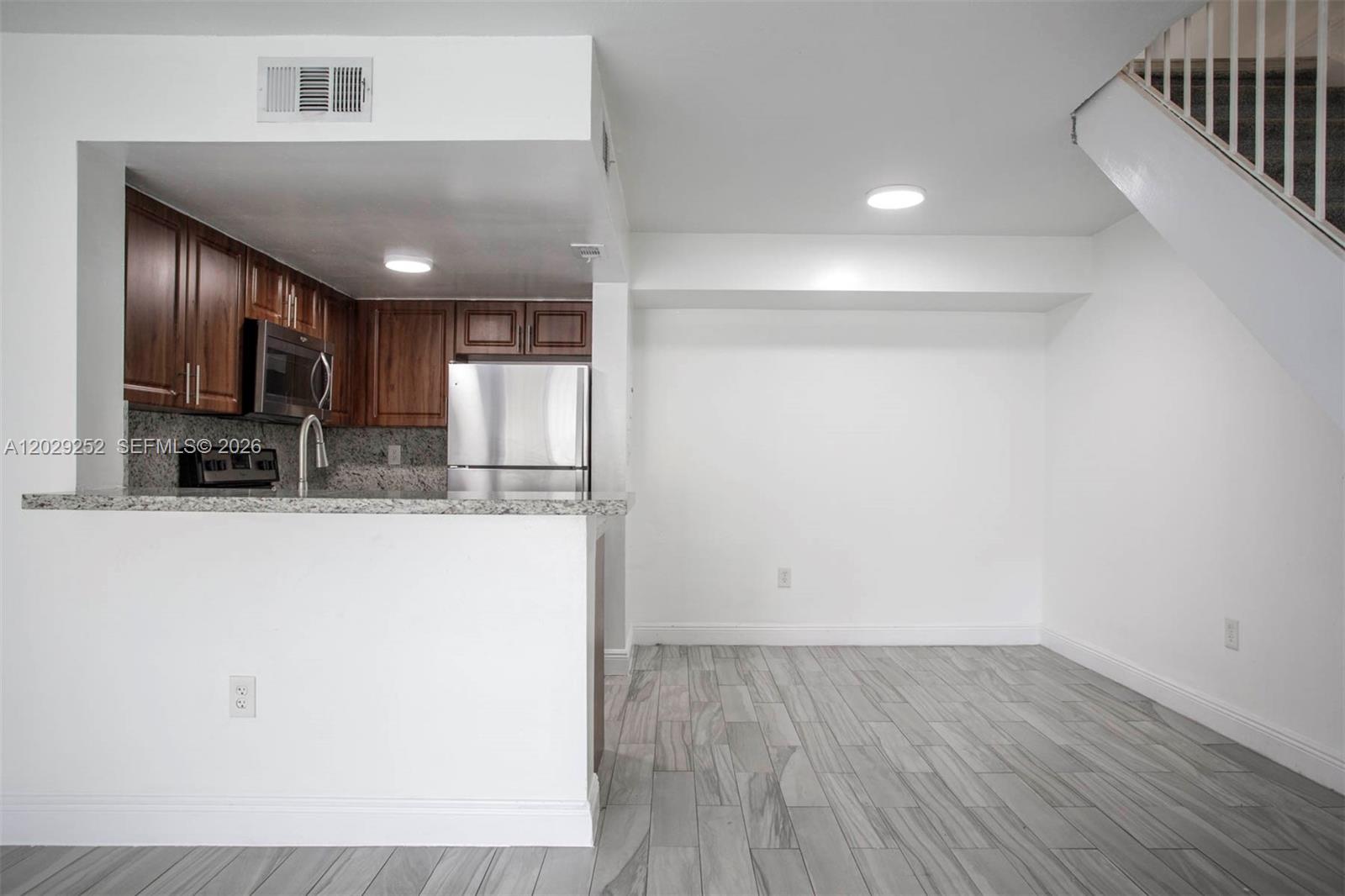 A kitchen with wood cabinets and stainless steel appliances overlooks an open dining area — 8580 NW 6th Ln # 205, Miami FL 33126, MIAMI, FL