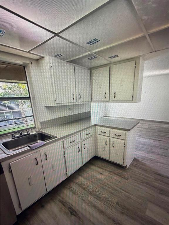 A kitchen features white cabinets, gray countertops, a stainless steel sink, and wood-look flooring — 4241 NW 19TH STREET UNIT 170, LAUDERHILL, FL