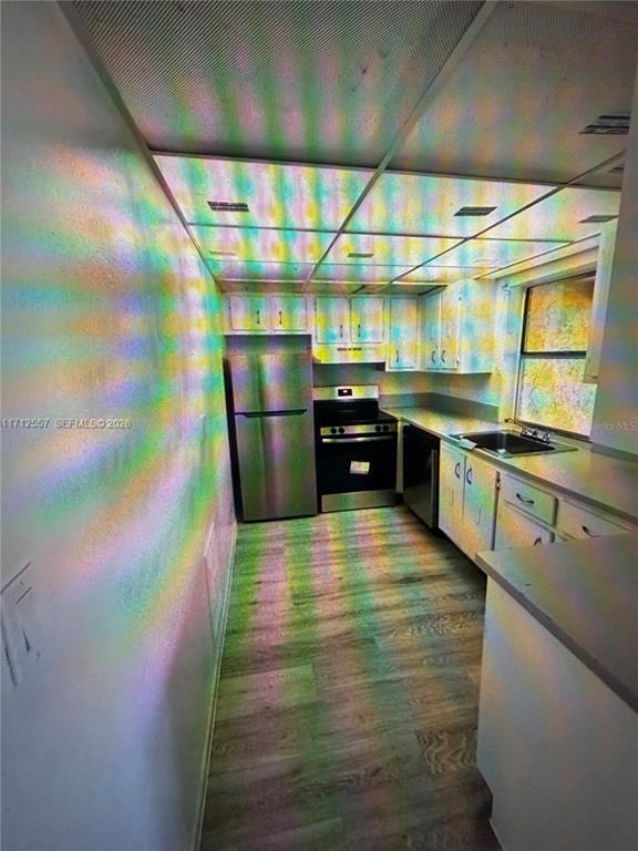 A galley kitchen features stainless steel appliances, white cabinetry, and light wood-look flooring — 4241 NW 19TH STREET UNIT 170, LAUDERHILL, FL