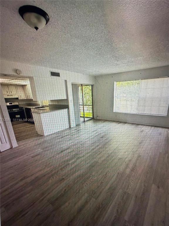 An open-concept living area features wood-look flooring, a kitchen with white cabinets, and a balcony — 4241 NW 19TH STREET UNIT 170, LAUDERHILL, FL