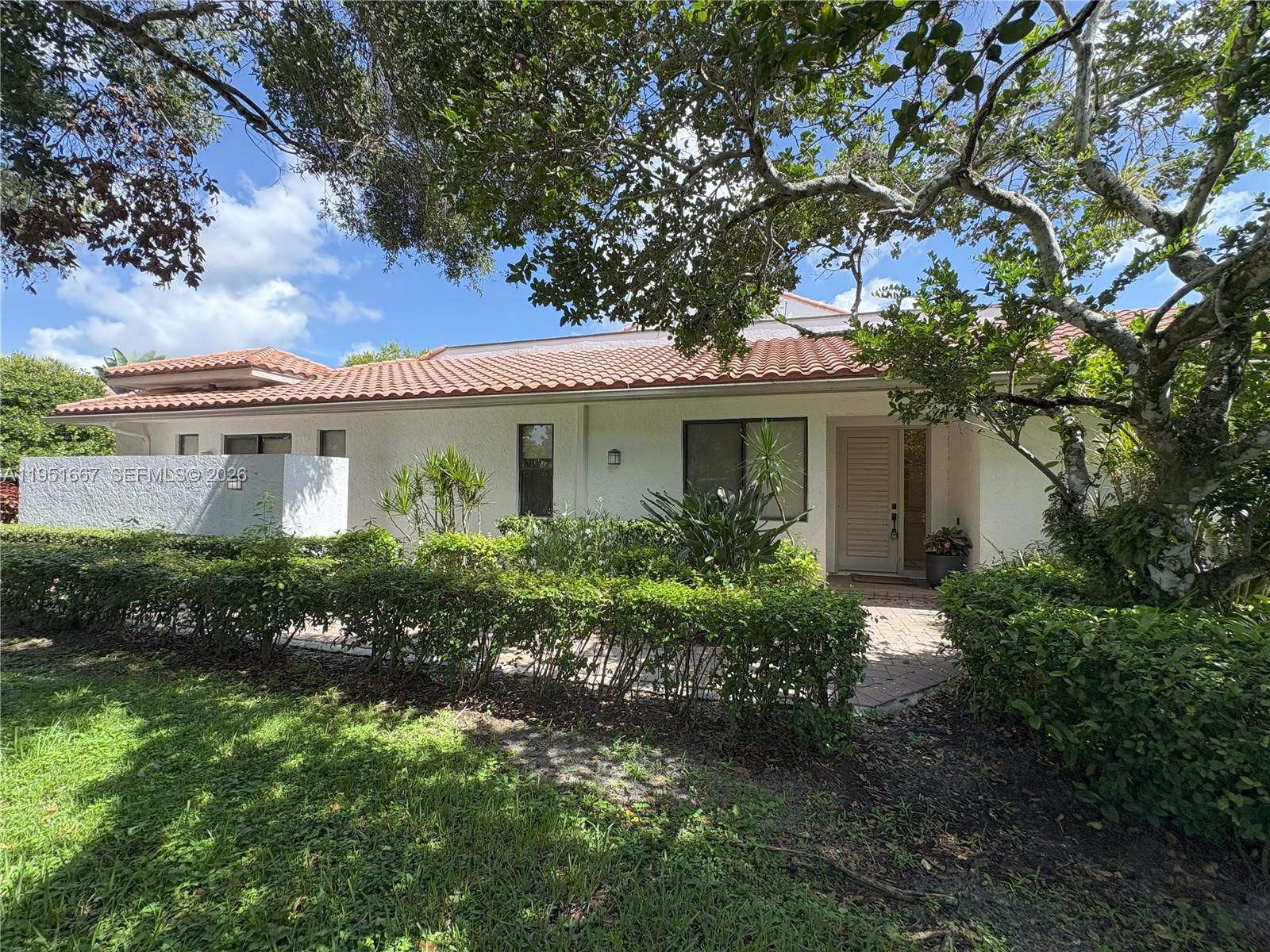 The exterior of a white house features a tiled roof, a front entrance, and landscaping — 2538 Windsor Way Ct, Wellington FL 33414, WELLINGTON, FL