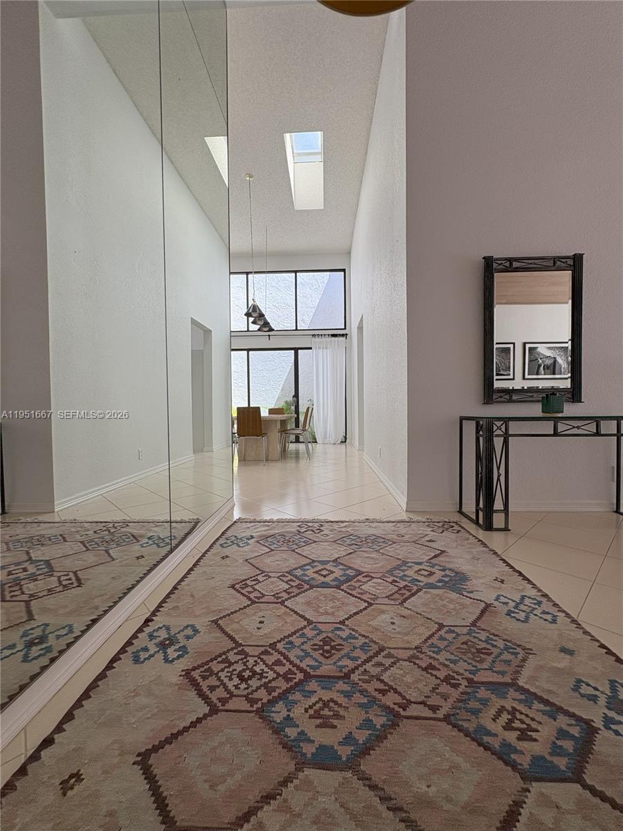 A tiled entryway features a large area rug, mirrored wall, and a view toward a dining area — 2538 Windsor Way Ct, Wellington FL 33414, WELLINGTON, FL