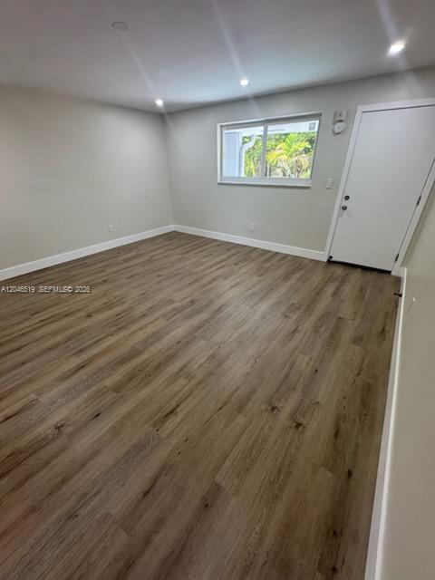 An empty room features light wood-look flooring, neutral walls, recessed lighting, and a white door — 6805 SW 88th St # 5, Pinecrest FL 33156, PINECREST, FL