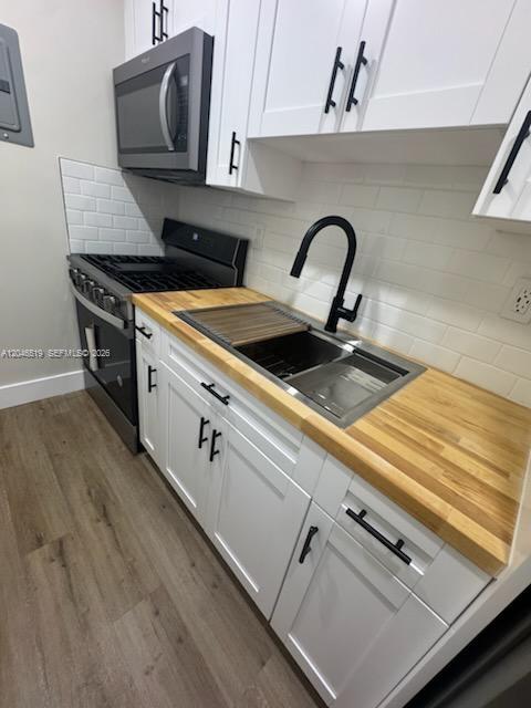 A kitchen features white cabinets, a wood countertop, a stainless steel sink, and a microwave — 6805 SW 88th St # 5, Pinecrest FL 33156, PINECREST, FL
