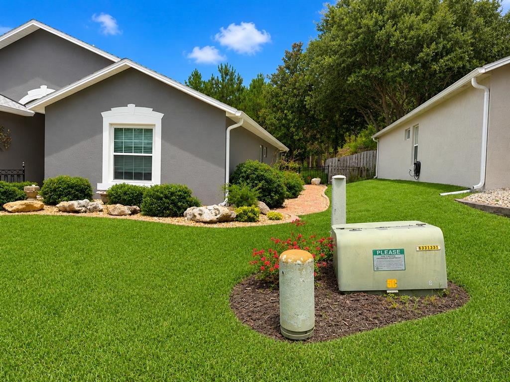 A gray house exterior with a green lawn and a utility box in the foreground — 239 CHINA BERRY CIRCLE, DAVENPORT, FL