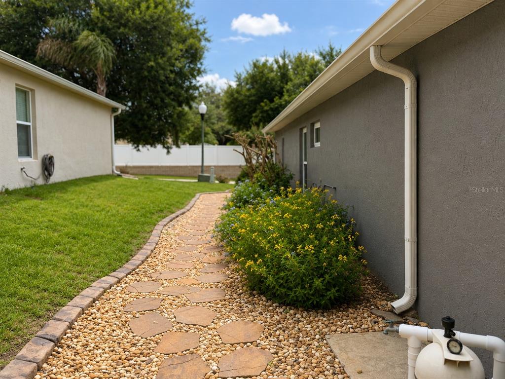 A stone path winds between a grassy lawn and a house with a gravel garden — 239 CHINA BERRY CIRCLE, DAVENPORT, FL