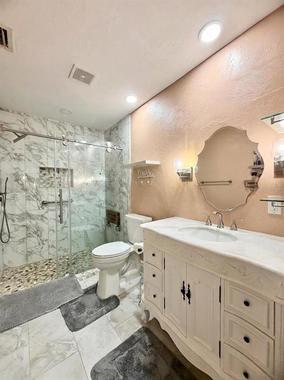 A bathroom features a marble-tiled walk-in shower, a white vanity, and a peach-colored wall — 10966 SW 85 TERRACE, OCALA, FL