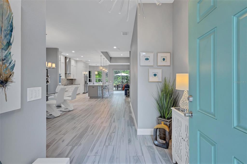 An entryway with a teal door opens into a modern kitchen and living area — 139 TALL TREES COURT, SARASOTA, FL